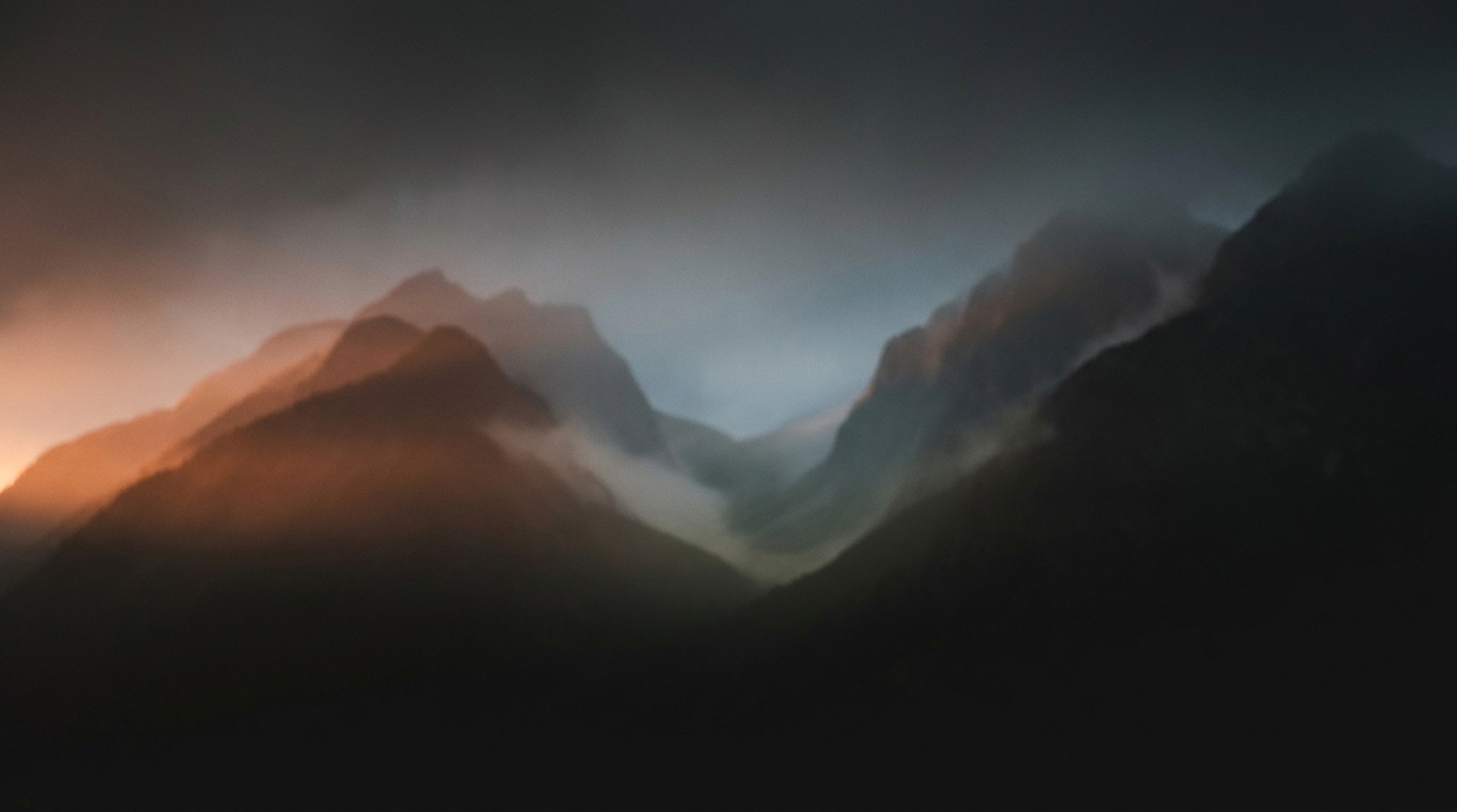 STEEP atmospheric ascent: moody dawn peaks dissolving into haze, a luminous valley opening between dark ridgelines